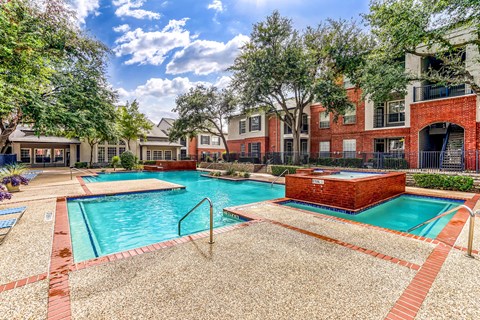 A swimming pool surrounded by a brick patio and trees.