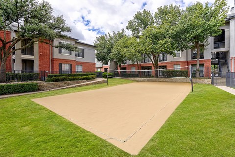 A playground with a sandy area and a green lawn.