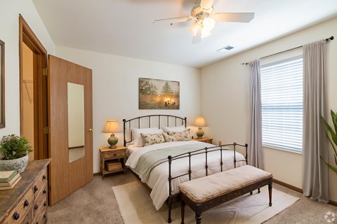 A bedroom with a bed, nightstands, and a ceiling fan.