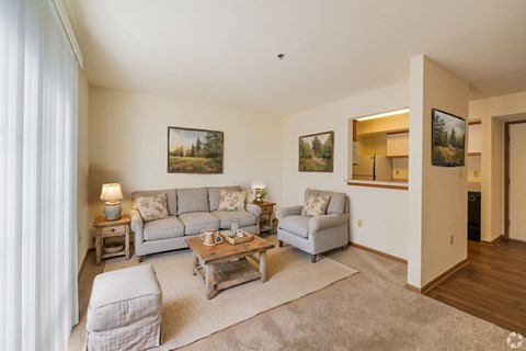 A living room with a grey couch, a chair, a coffee table, and pictures on the wall.