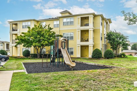 A yellow apartment building with a playground in front.