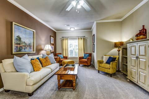 A living room with a white couch, a yellow chair, and a painting on the wall.