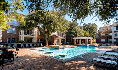 A pool surrounded by trees and chairs.
