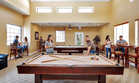 A group of people playing pool in a room.