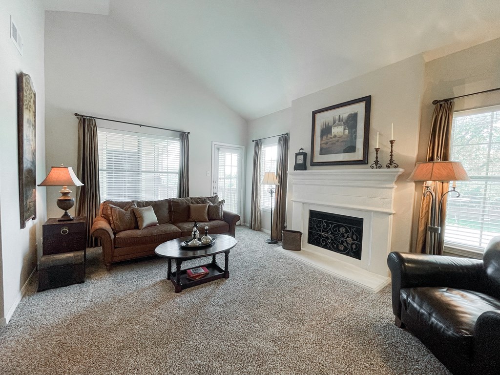 Living room with beige carpeting and fireplace at SaddleBrook Apartments, Dallas, Texas