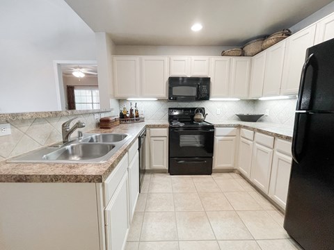 a kitchen with white cabinets and black appliances