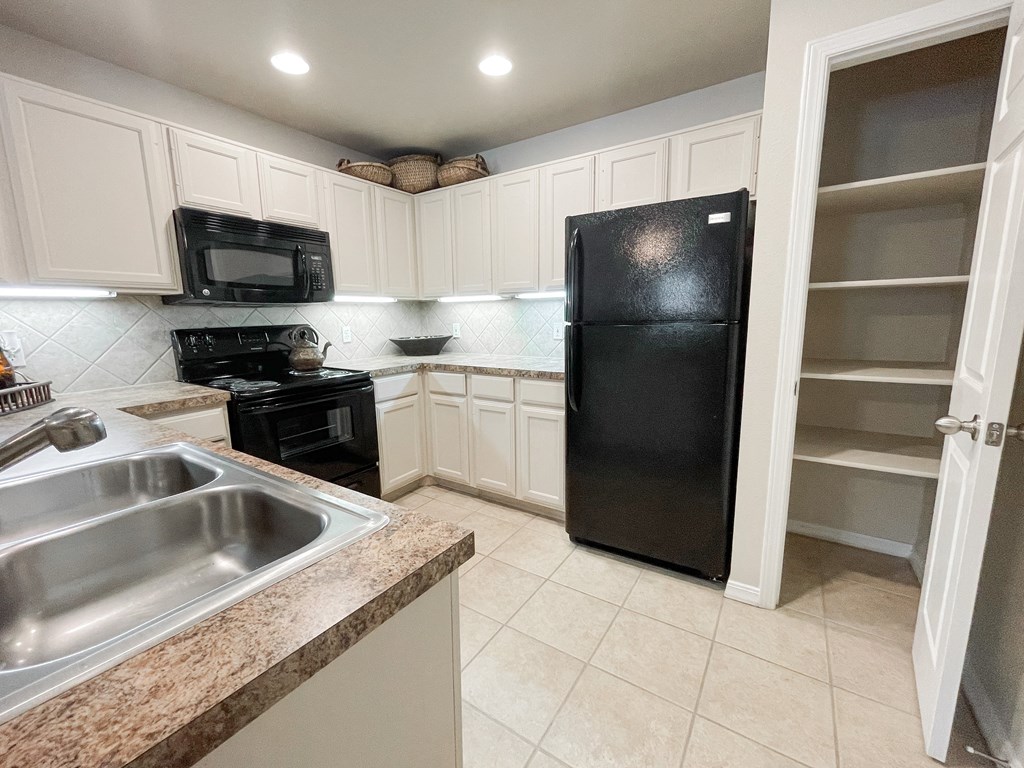 Kitchen with white cabinets and black appliances at SaddleBrook Apartments, Dallas