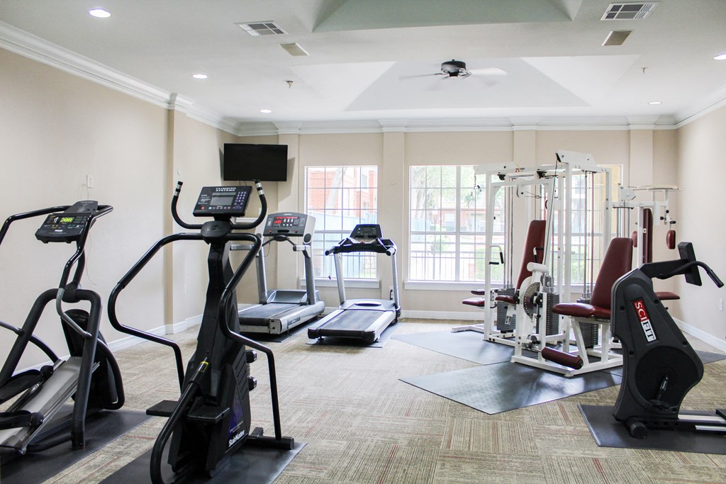 On site fitness center with cardio machines and ample natural lighting at Montfort Place Apartments, Dallas