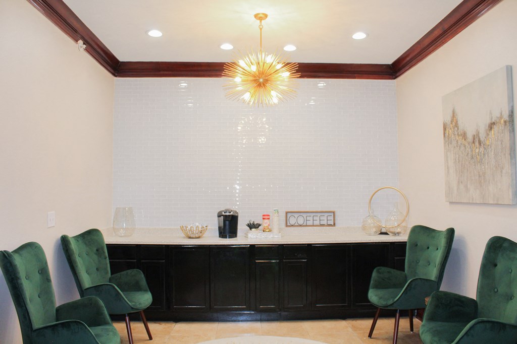Interior of leasing office coffee bar with green chairs and white countertop with black cabinets containing refreshments at Montfort Place Apartments, Dallas, TX, 75254
