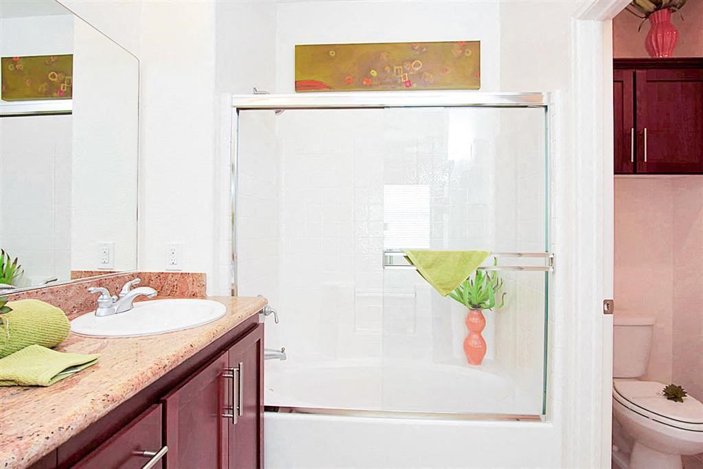 a bathroom with a shower with white tile and a glass door at Croix Townhomes, Henderson