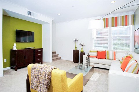 A living room with a yellow chair and a glass coffee table.