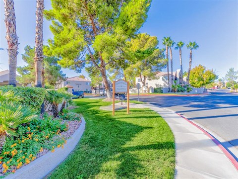 Outdoor walking area with welcome signage and green grass at Country Club at Valley View - 55+ Senior Community Apartments, Las Vegas, Nevada