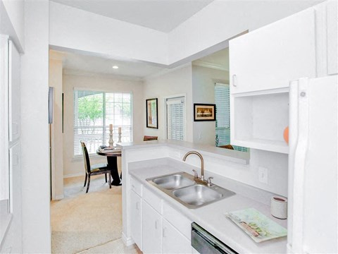 a white kitchen with a sink and a window