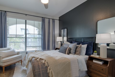 A bedroom with a bed, chair, and window.