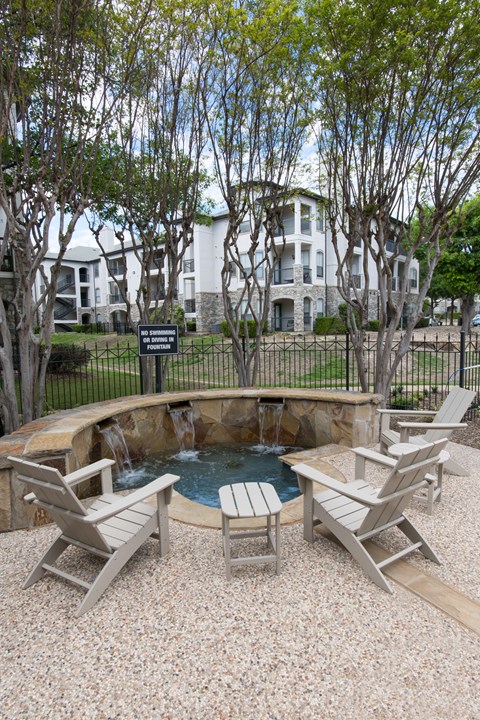 A backyard with a hot tub and chairs.