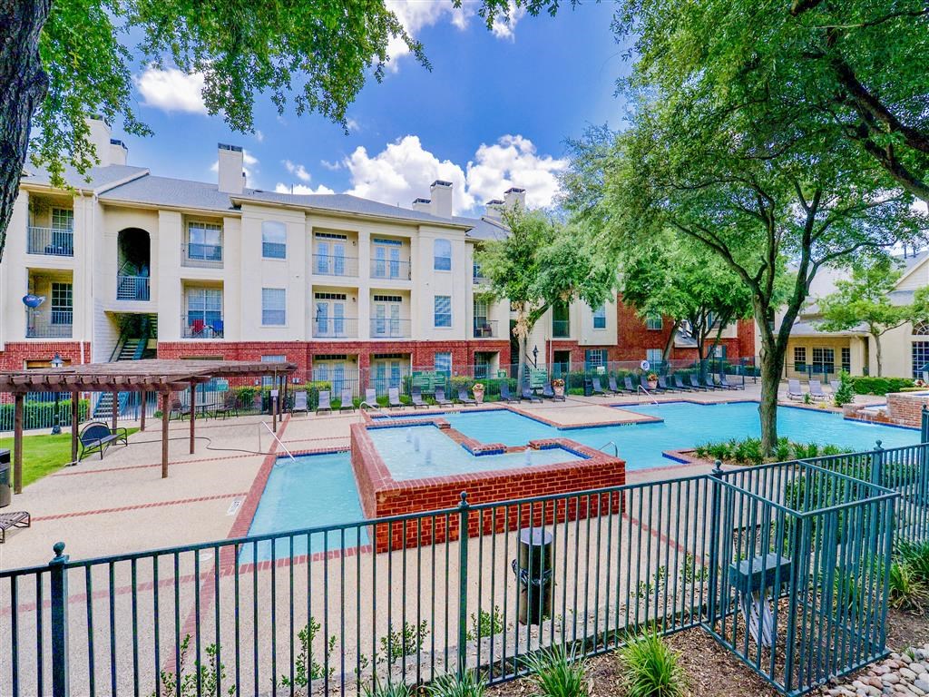  View of the gated resort style swimming pool and hot tub with lounge chairs at Montfort Place Apartments, Texas