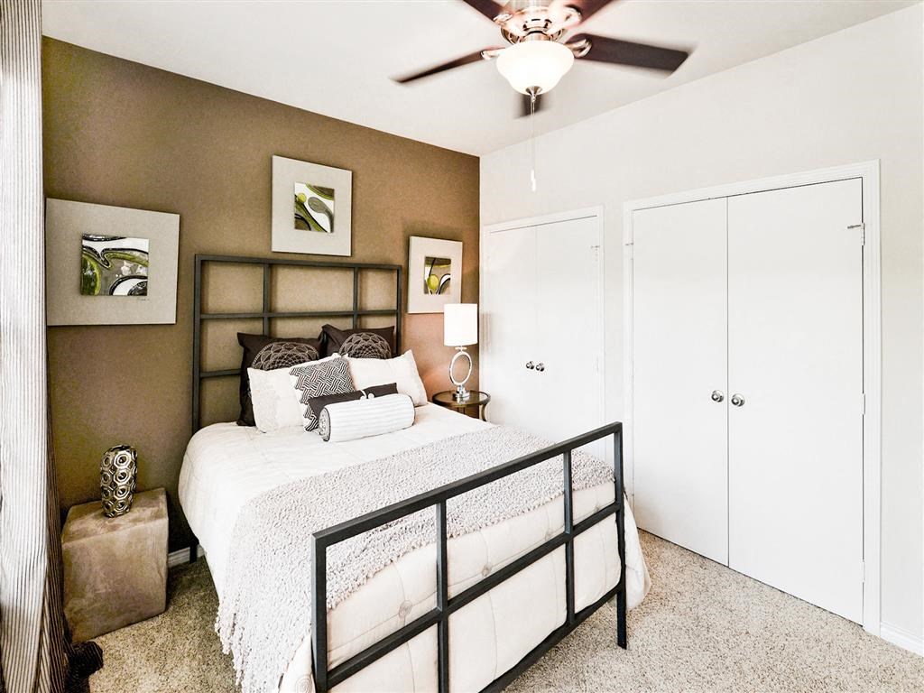 Expansive bedroom with beige carpet, white closets, a queen sized bed and a ceiling fan at Mission at La Villita Apartments, Irving, TX, 75039