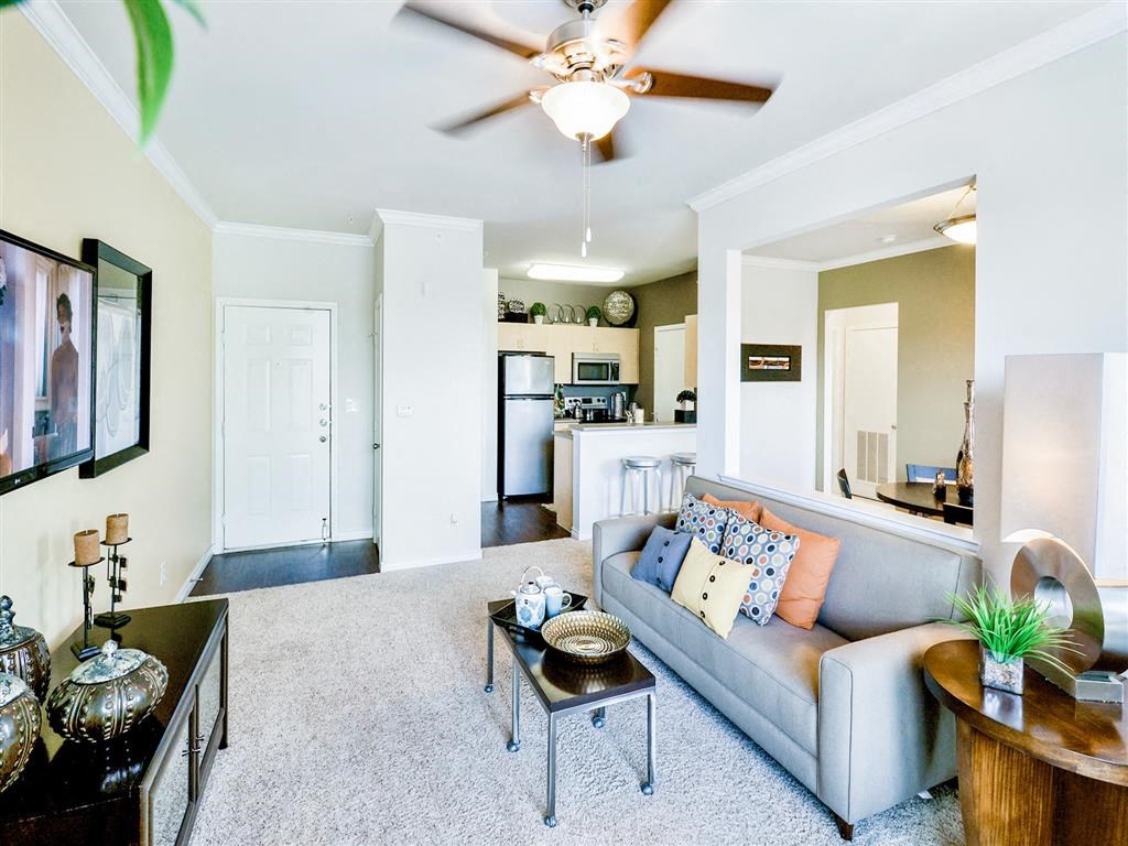 Interior living room with small brown coffee table, a side table, a beige couch and ceiling fan at Mission at La Villita Apartments, Irving 75039