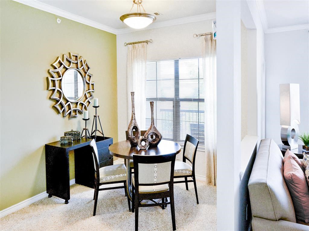 Interior dining room located next to tall windows, mirror, table and 4 tan chairs at Mission at La Villita Apartments, Texas