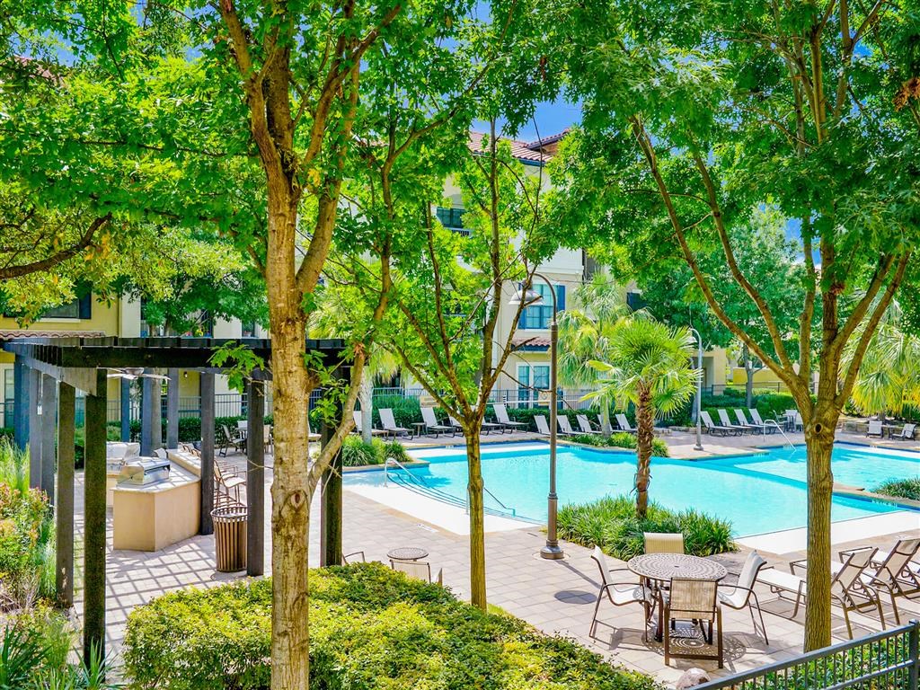 Sparkling pool surrounded by trees at Mission at La Villita Apartments in Irving, TX offers 1, 2 & 3 bedroom apartment homes with appliances at Mission at La Villita Apartments, Irving, TX, 75039