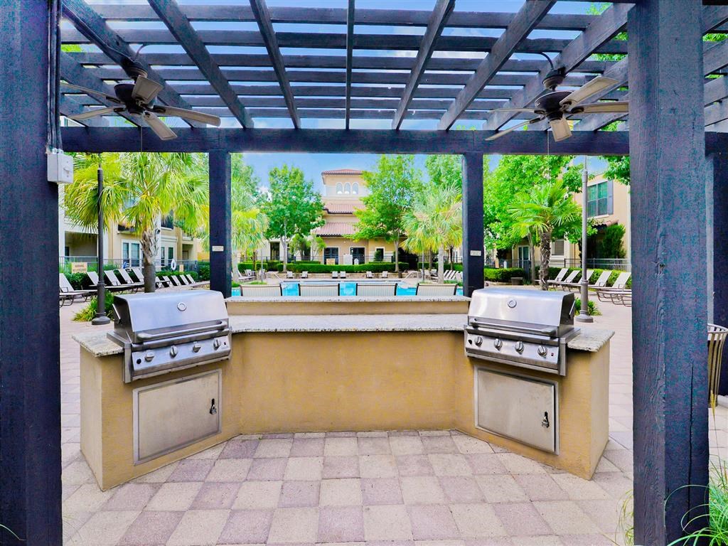 Outdoor grilling area with a blue covering at Mission at La Villita Apartments, Irving, TX