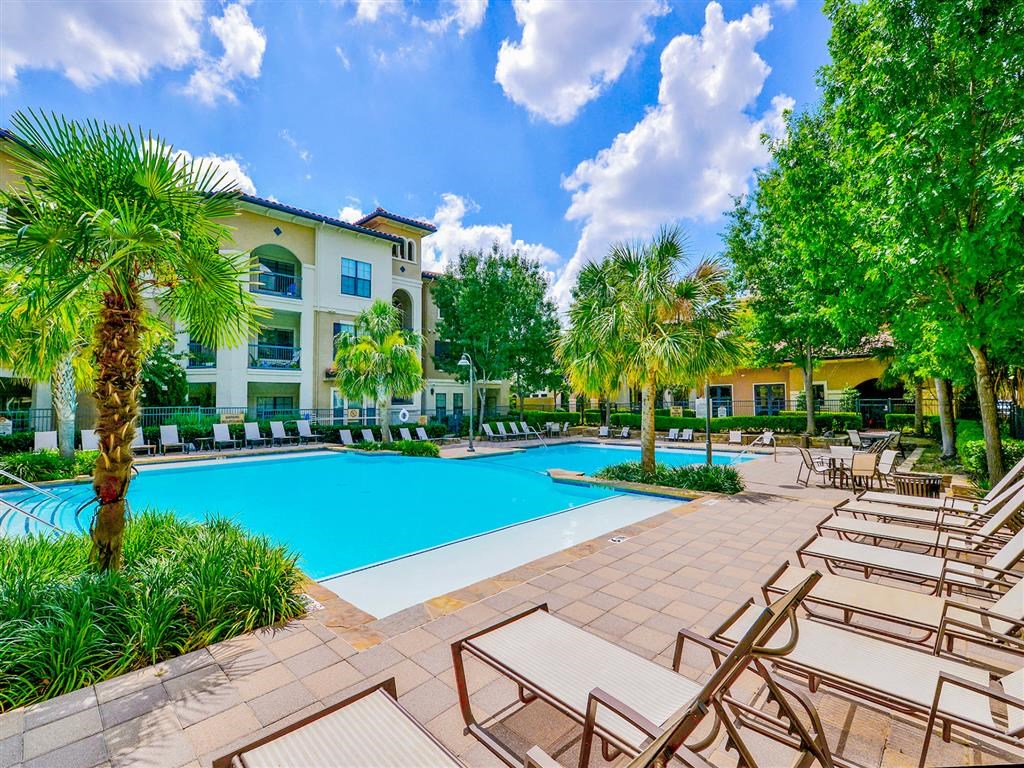 Outdoor pool with white lounge chairs  at Mission at La Villita Apartments, Irving, Texas