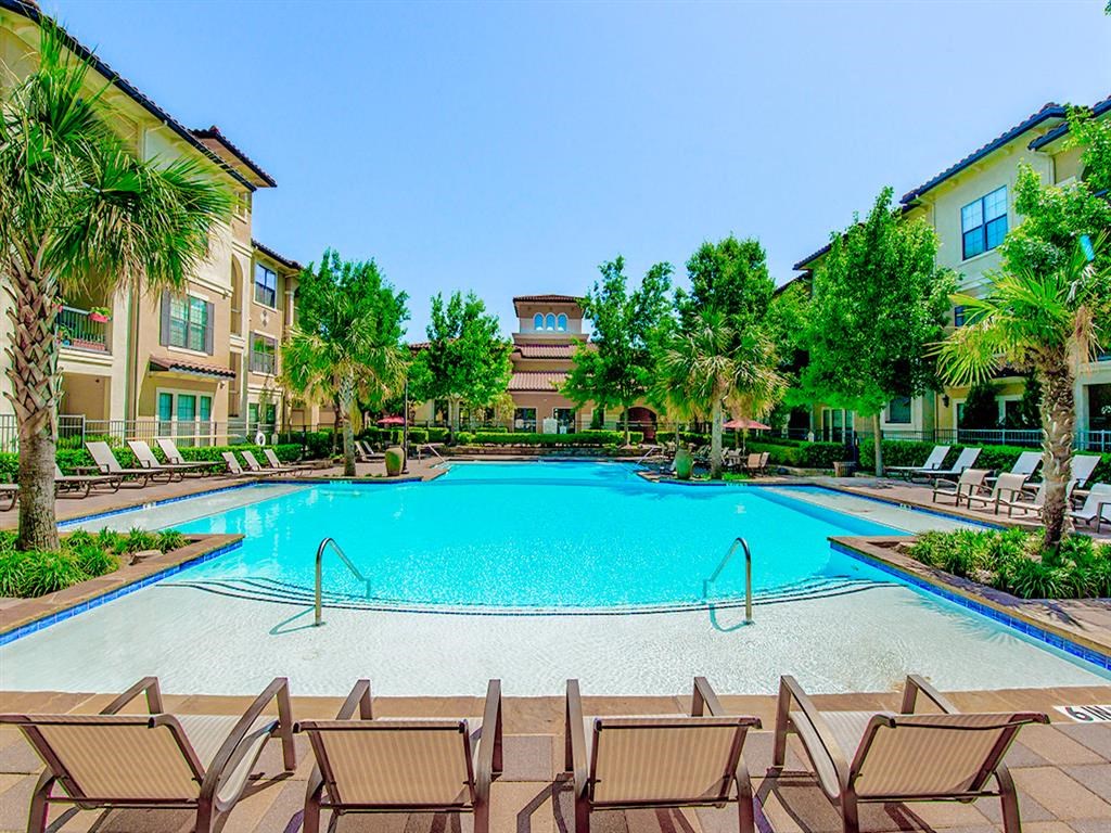 Outdoor pool with tan stone walkways and palm trees surrounding it  at Mission at La Villita Apartments, Texas, 75039