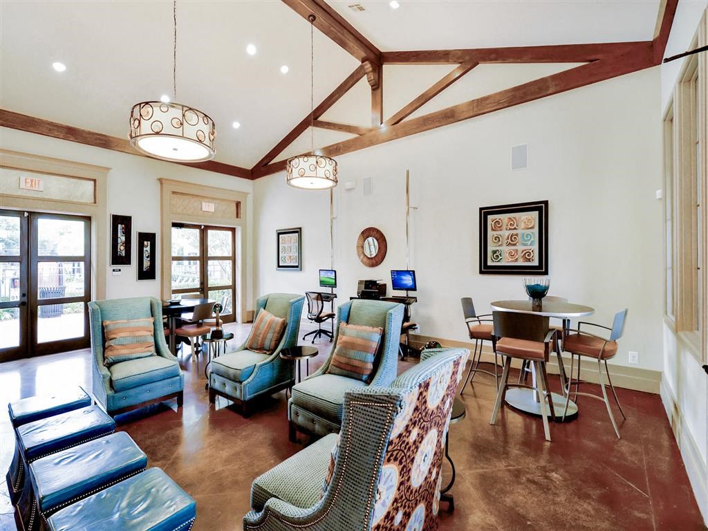 Community clubhouse with ample seating, soaring ceilings, hardwood floors, natural lighting and plenty of chairs and tables at Mission at La Villita Apartments, Irving, Texas