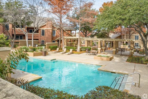 A large swimming pool surrounded by a patio and trees.
