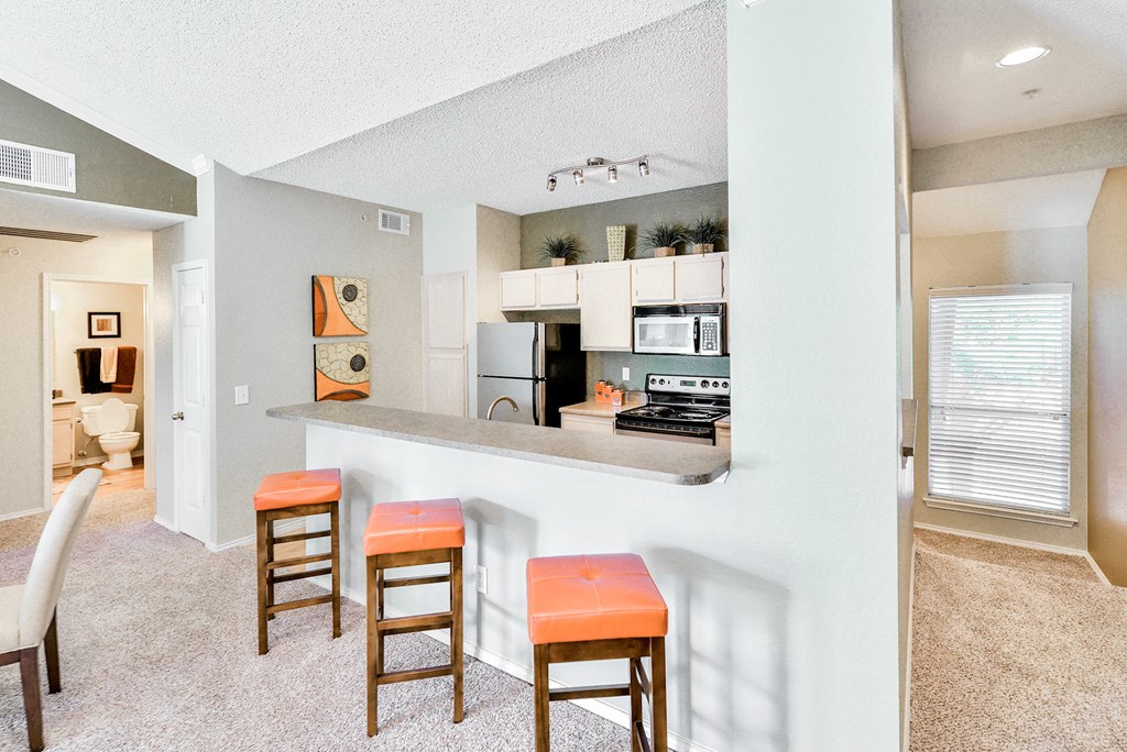 Interior kitchen view with kitchen countertop and orange seating at Winsted at Valley Ranch, Texas