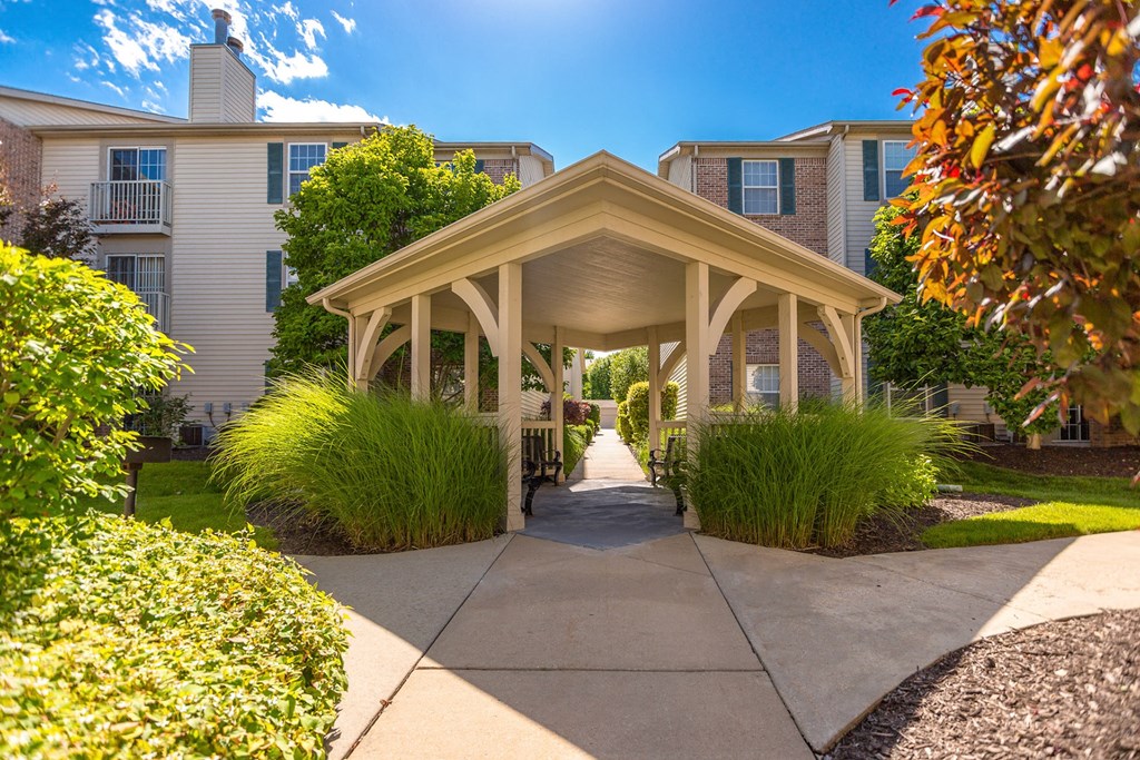A gazebo-like structure is in the middle of a walkway between two buildings at Prairie Commons - 55+ Senior Community Apartments, Lawrence, Kansas