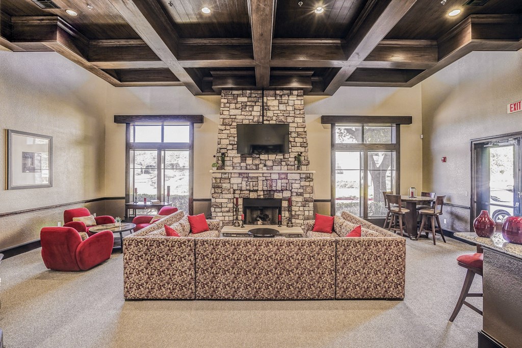 Large community clubhouse with a large couch overlooking a fireplace at Cypress Lake at Stonebriar in Frisco, TX!