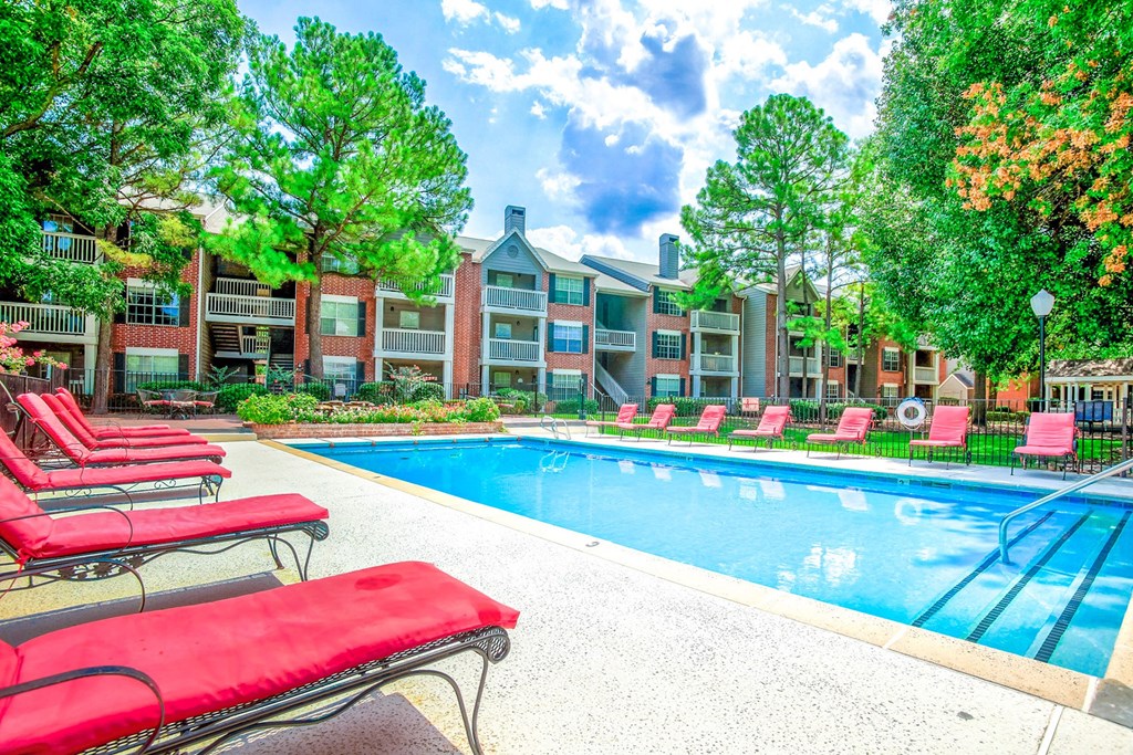 Outdoor swimming pool with red lounge chairs at Greenbriar Apartments, Tulsa, OK