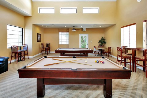 a game room with a pool table and two billiard tables