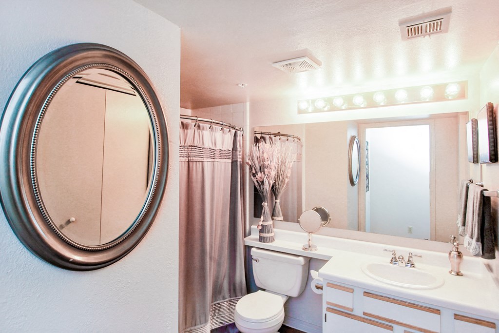 Bathroom with white walls and two mirrors at Riverside Park Apartments, Tulsa, Oklahoma