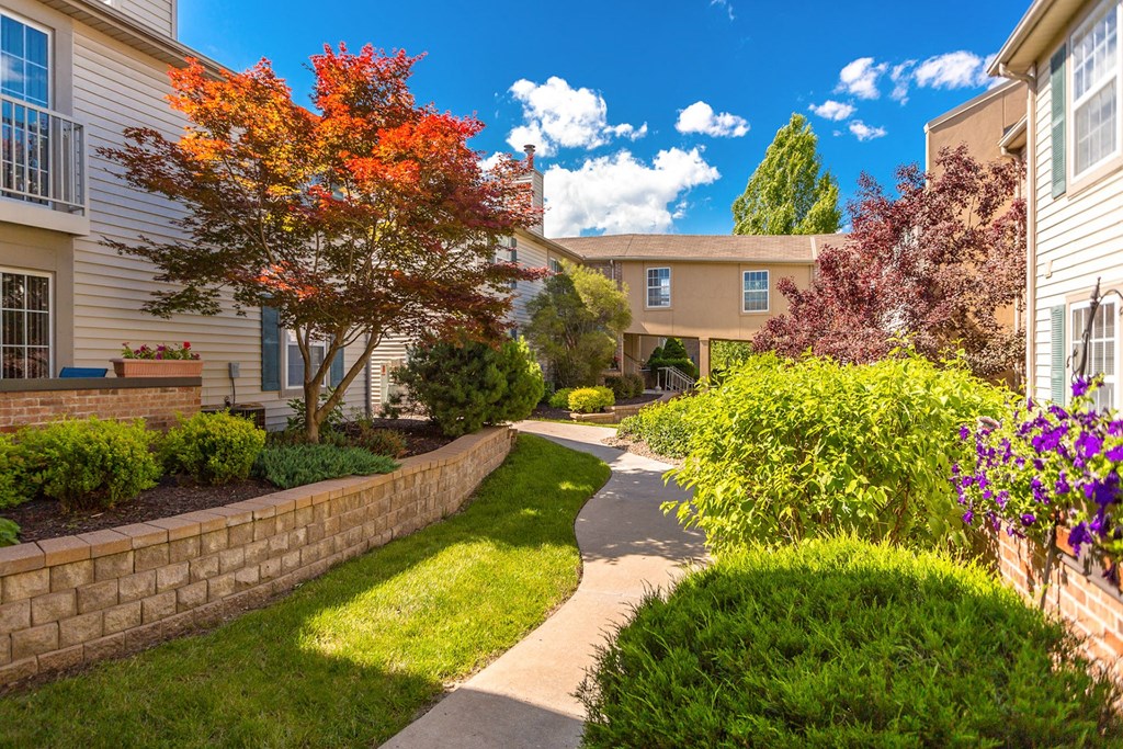 A tree with orange leaves is in front of a building at Prairie Commons - 55+ Senior Community Apartments, Lawrence 66049