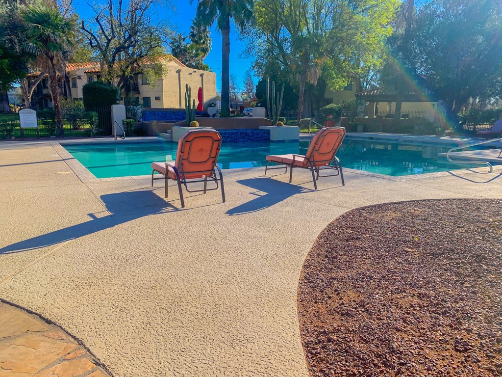 Outdoor swimming pool with orange lounge chairs at La Hacienda Apartment, Tucson, 85712