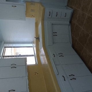 A white cabinet with drawers and a yellow cabinet with drawers are in a room.