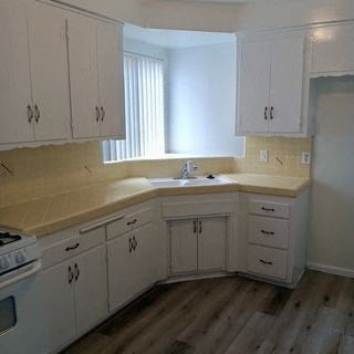 A kitchen with white cabinets and a wooden floor.