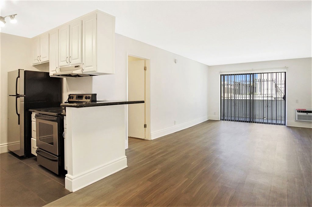 an empty living room and kitchen with a stove and refrigerator