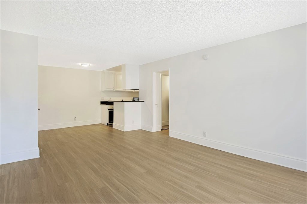 an empty living room and kitchen with wood flooring
