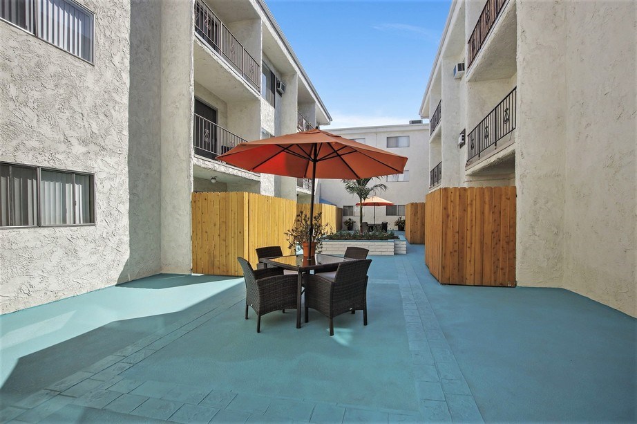 a patio with a table and chairs under a red umbrella