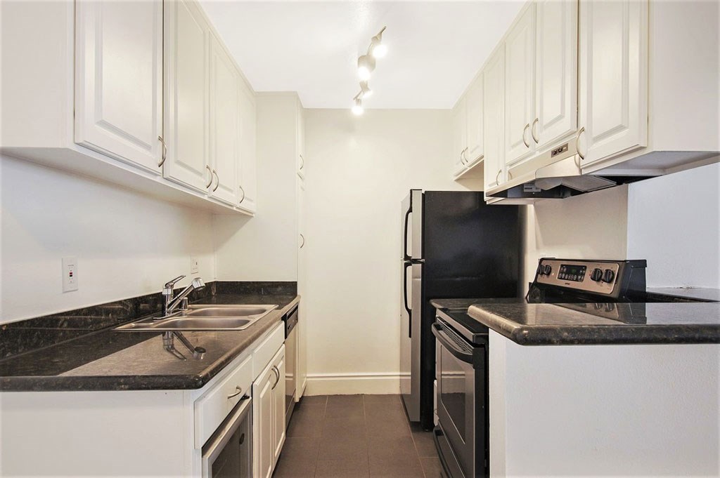 a kitchen with white cabinets and black appliances