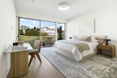 a bedroom with a bed and a desk and sliding glass doors