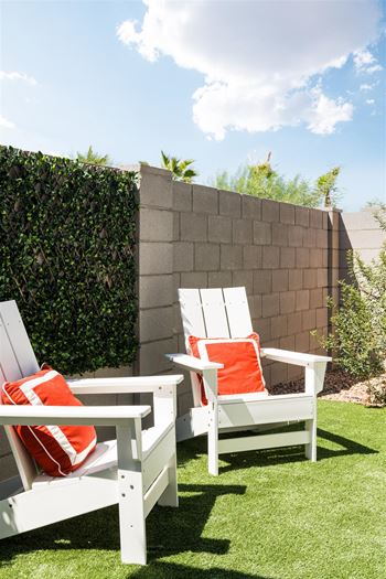 a backyard with white chairs and orange pillows at Villas on Ash, Gilbert, AZ  