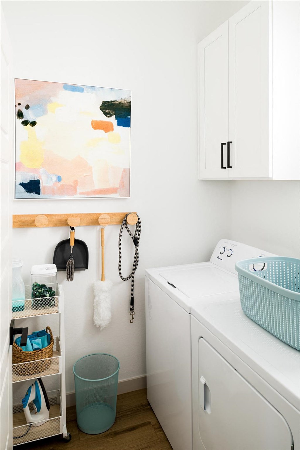 a small laundry room with a washing machine and a painting on the wall