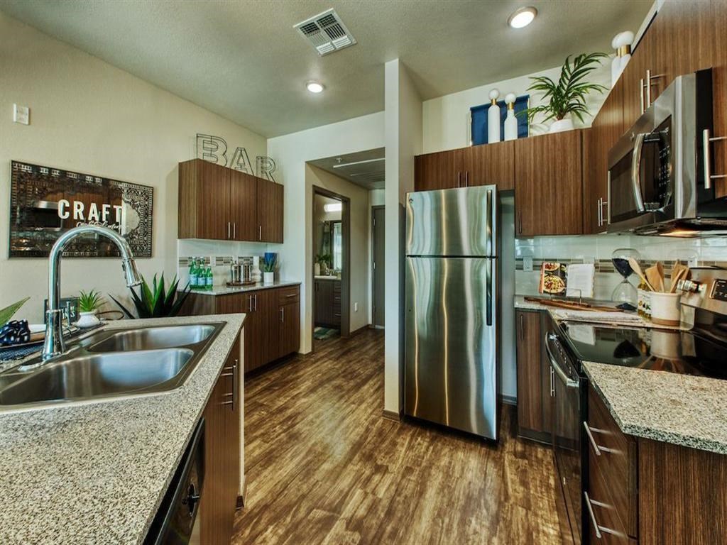 kitchen with stainless steel double sink and stainless steel refrigerator. Beautiful modern cabinets line kitchen walls and surround black range. kitchen with stainless steel double sink and stainless steel refrigerator. Beautiful modern cabinets line kitchen walls and surround black range.at Craft at Gilbert and Baseline, Arizona, 85204