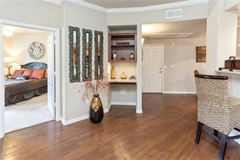 Superstition Canyon Model Entry Photo of a model apartment showing the entryway, bedroom on the left with queen bed and kitchen bar on the right. - Photo Gallery 4