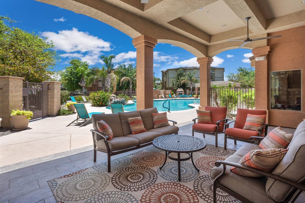 A patio with a couch, chairs, and a table with a rug.