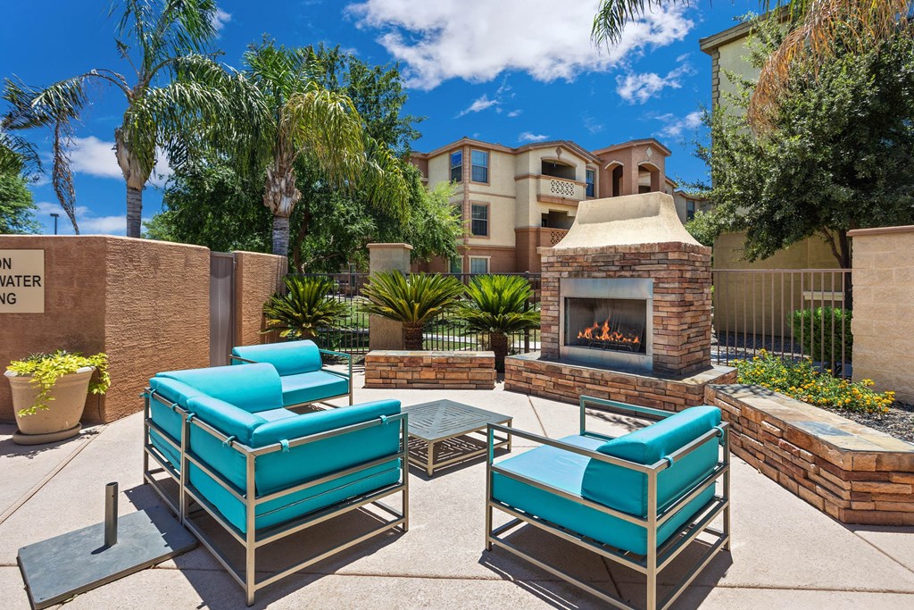 A patio with a fireplace and two chairs.